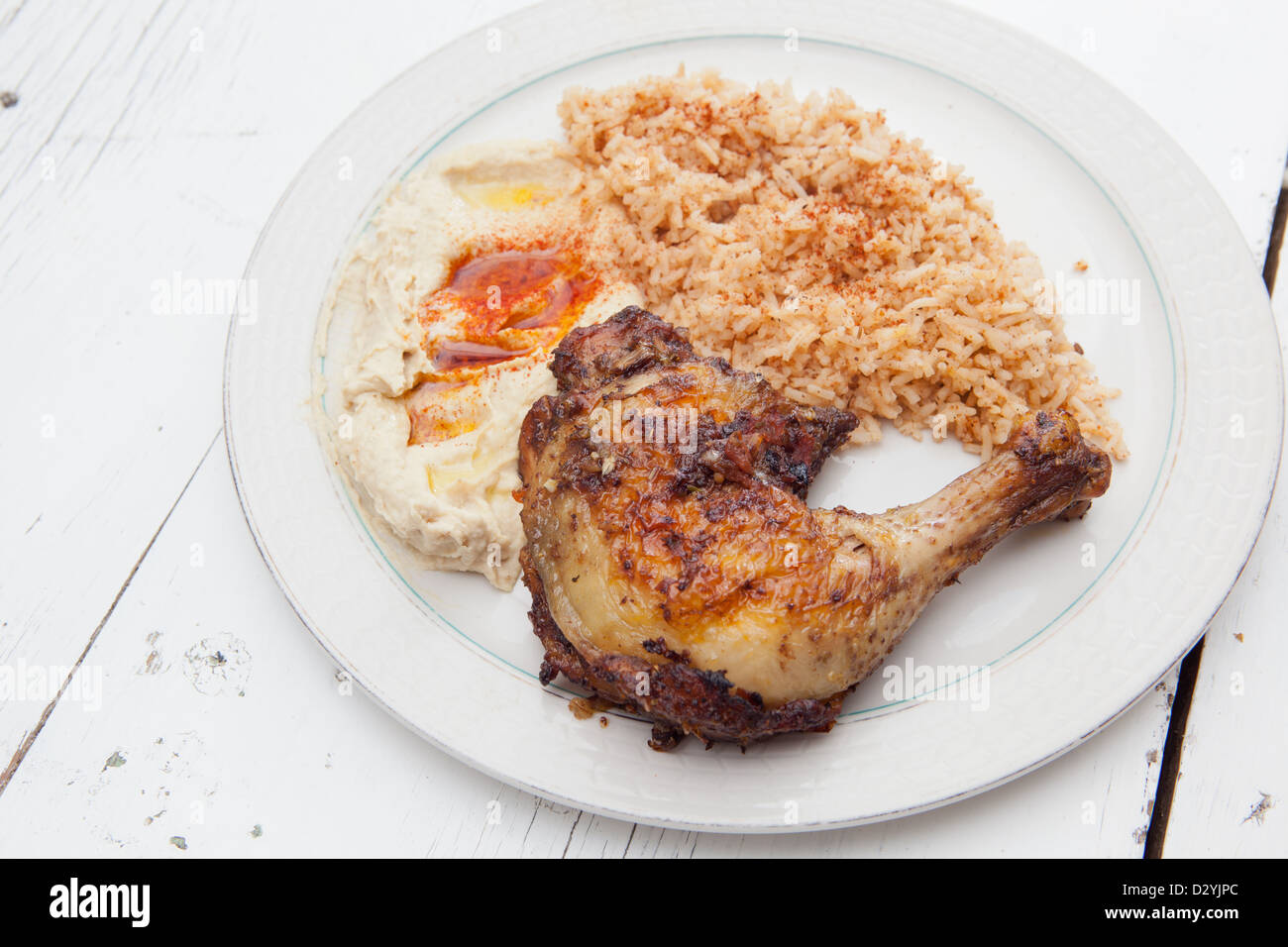 Piastra della cena per uno con un arrosto di pollo piccante, autentico stile mediterraneo riso servito con hummus e rabboccato con olio. Foto Stock