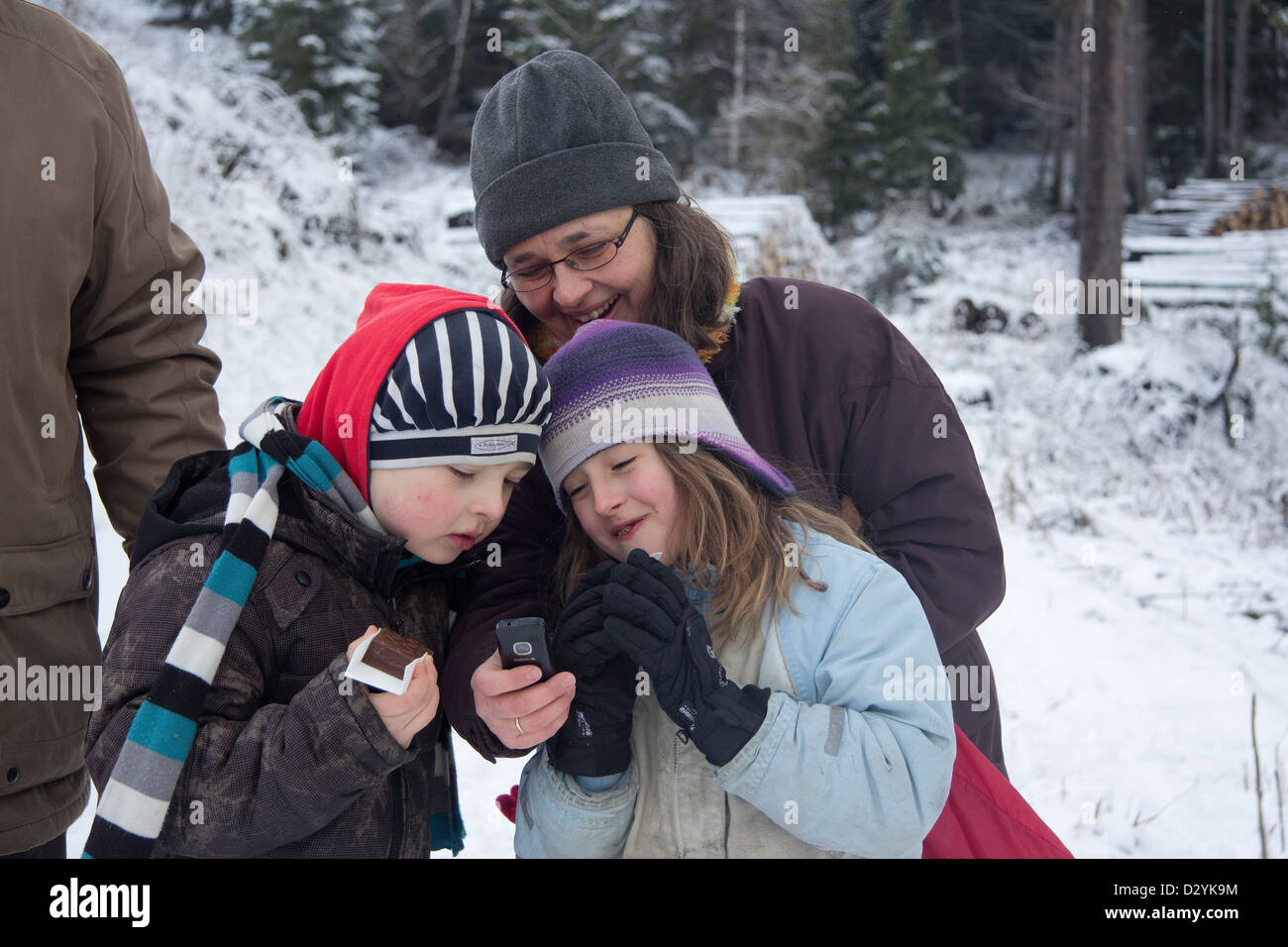 Madre e bambini guardando le loro foto sul telefono cellulare Foto Stock