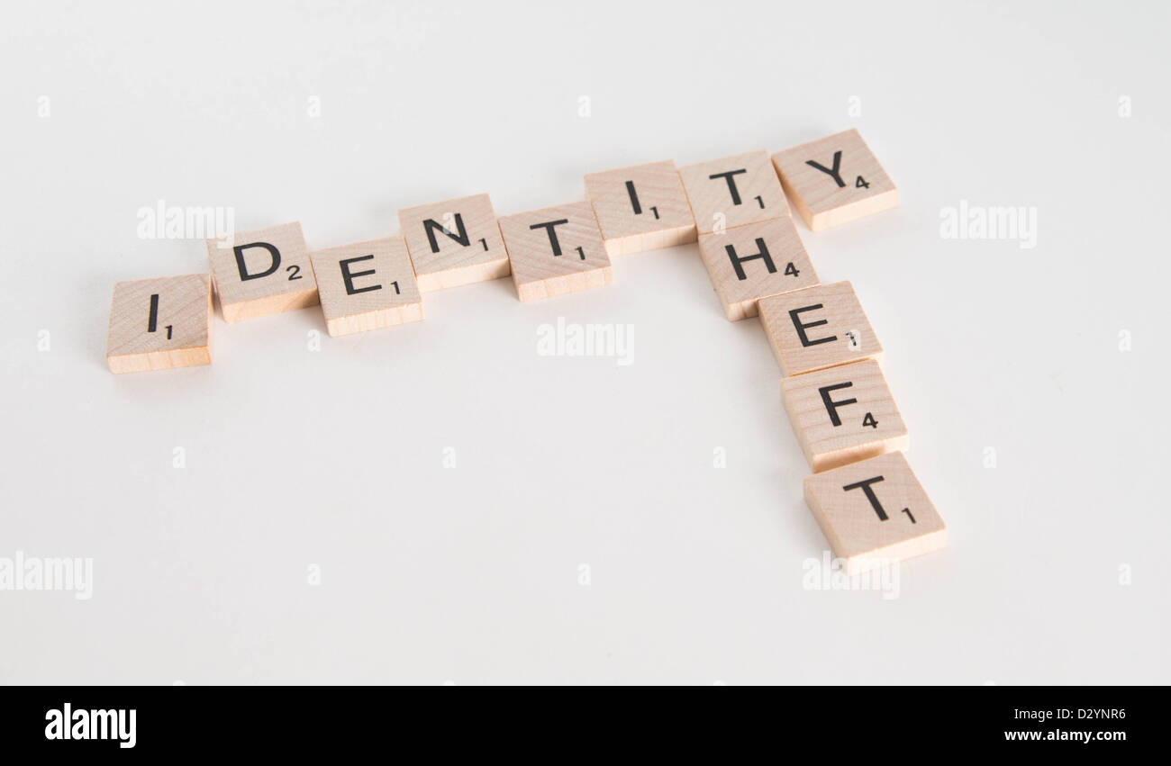 Il furto di identità scritto in lettere di Scrabble con passaporto statunitense al di fuori della messa a fuoco in background. Isolato su sfondo bianco. Foto Stock