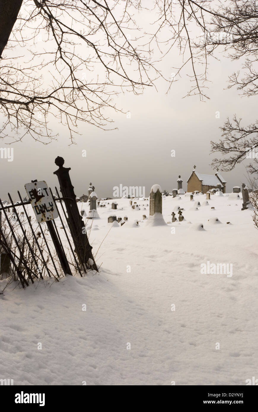 Creepy cimitero in oscurità su una giornata invernale e con l'uscita solo segno. Foto Stock