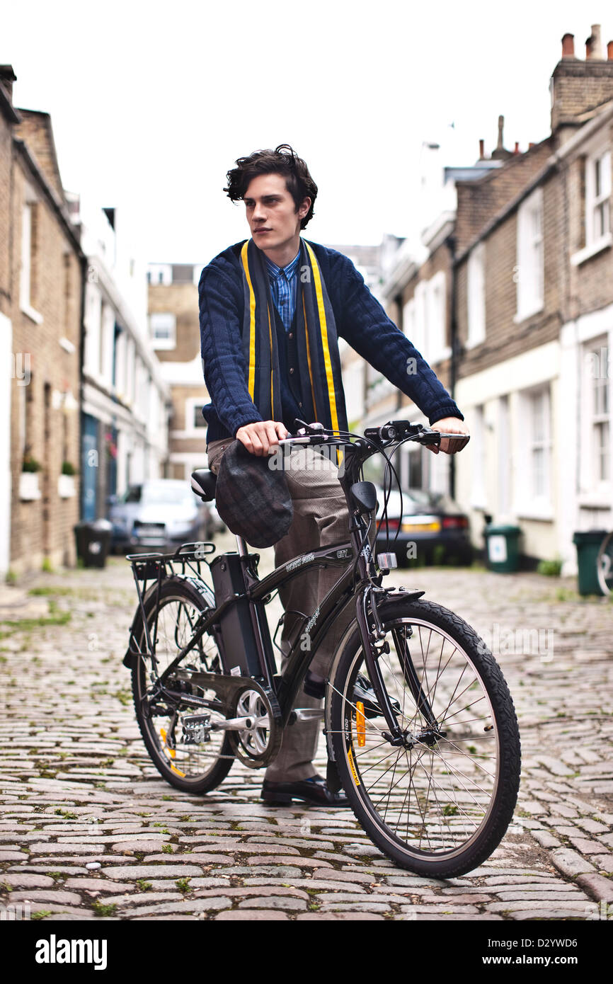 L'uomo con la bicicletta elettrica in strada di ciottoli, London, Regno Unito Foto Stock