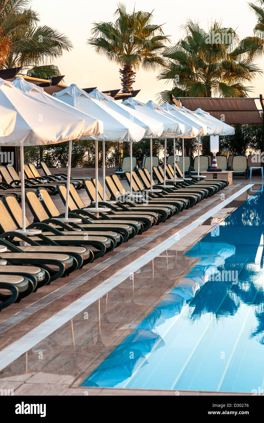 La mattina presto una piscina esterna con lettini da mare e ombrelloni nel resort di lusso Foto Stock