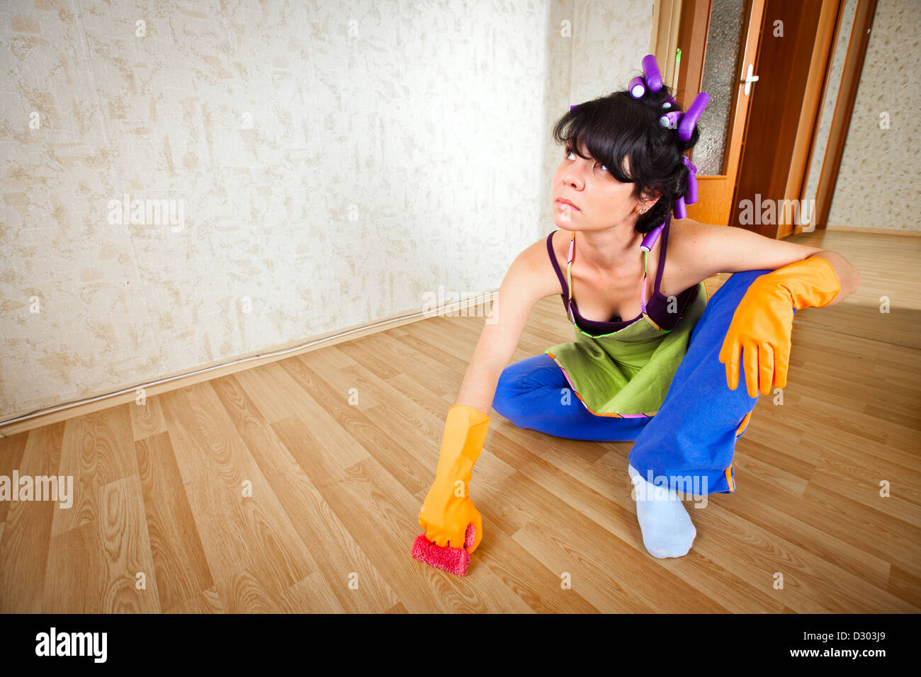 La casalinga si siede sul pavimento e la pulizia di un pavimento Foto Stock