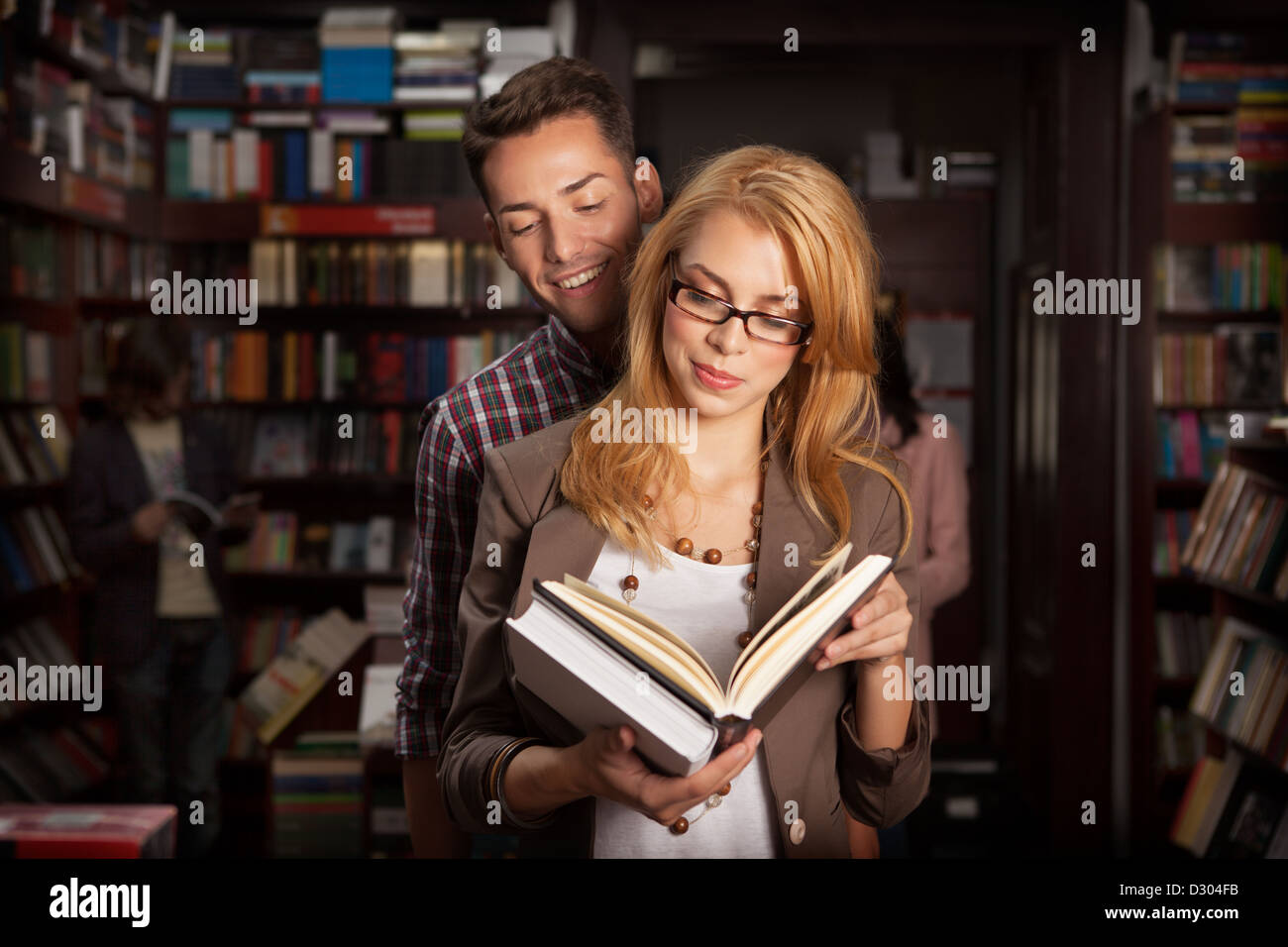Close-up di attraente coppia giovane in una libreria a leggere un