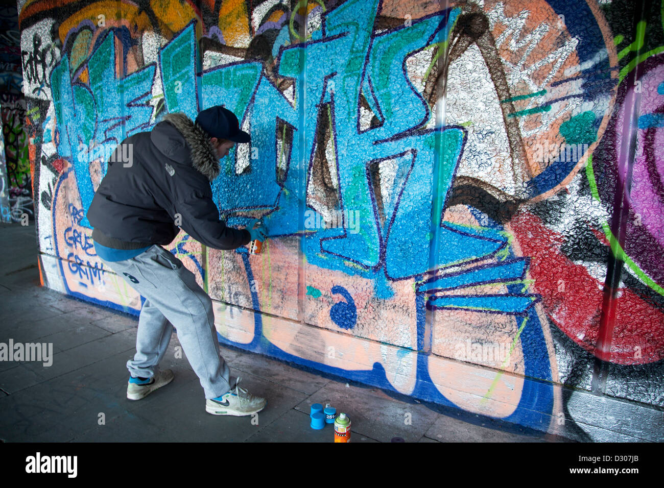 Un artista di graffiti spruzza un nuovo pezzo. Parte del Southbank noto come sotto-croft. Regno Unito home di Urban e la cultura di strada. Foto Stock