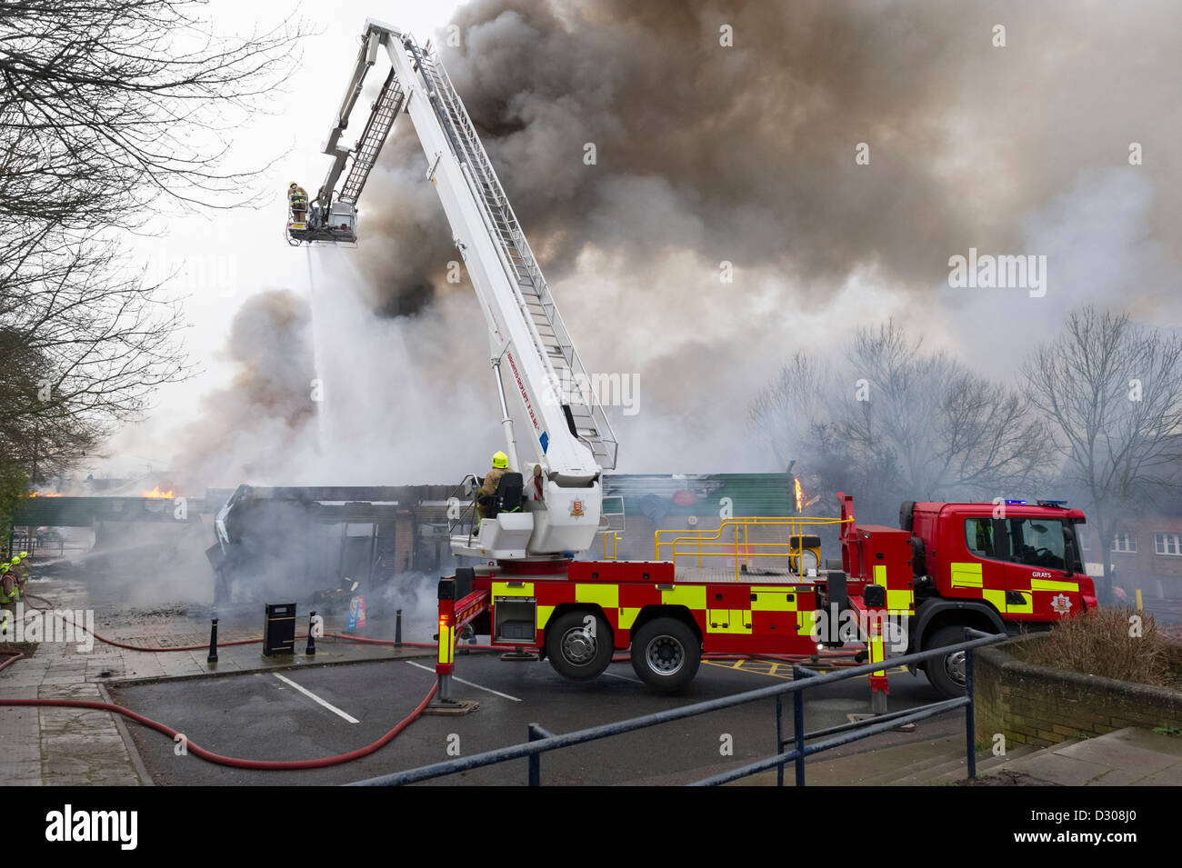 I vigili del fuoco su una scaletta della piattaforma girevole da un motore fire affrontare un tripudio in Inghilterra, Regno Unito Foto Stock