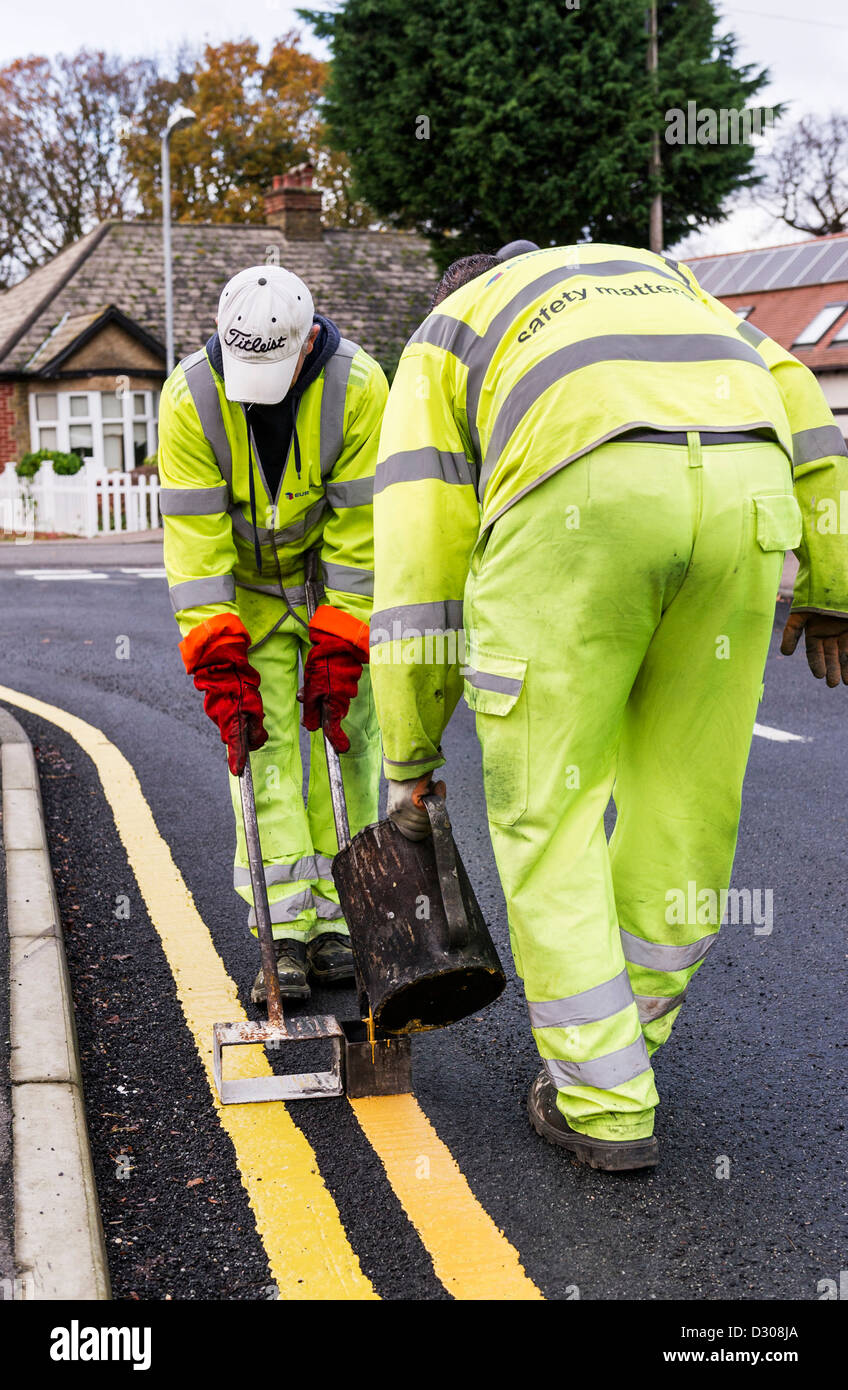 I lavoratori stradali che stabilisce le doppie linee gialla della segnaletica stradale su una strada, REGNO UNITO Foto Stock