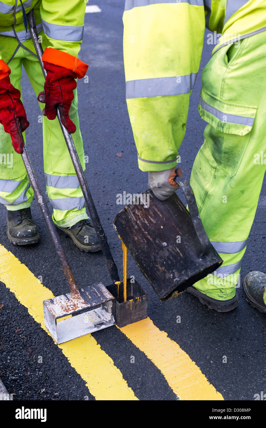 I lavoratori stradali pittura doppie linee gialla della segnaletica stradale su una strada, REGNO UNITO Foto Stock