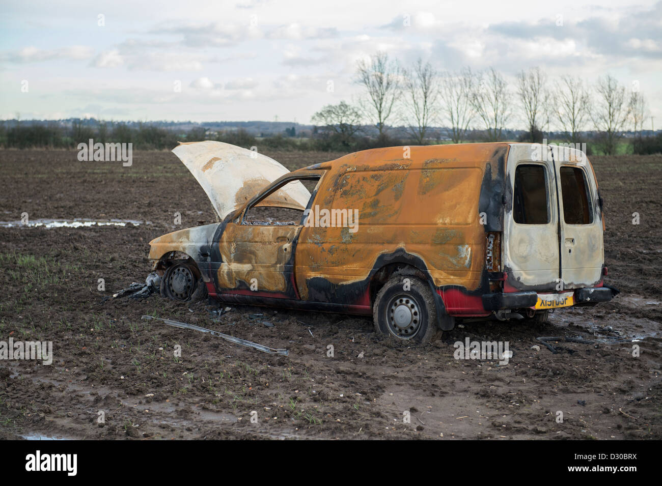 Immagine di bruciato Ford Escort van in un campo fangoso su terreni agricoli a Battlesbridge, Essex, Regno Unito. Foto Stock