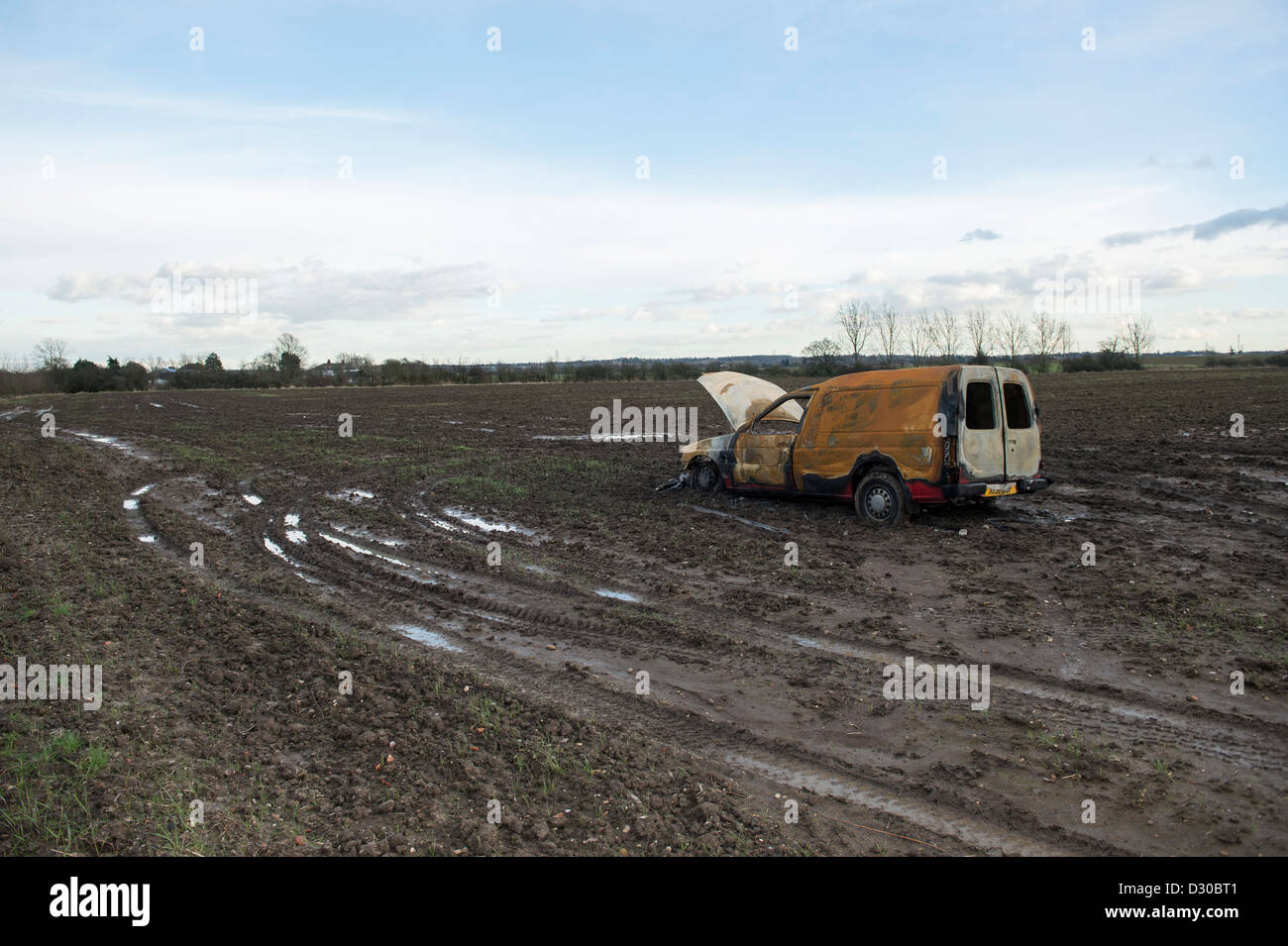 Immagine di bruciato Ford Escort van in un campo fangoso su terreni agricoli a Battlesbridge, Essex, Regno Unito. Foto Stock