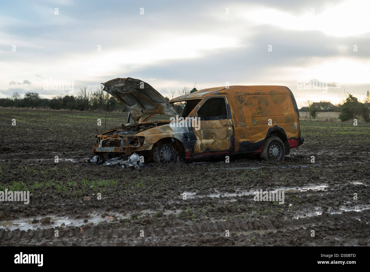 Immagine di bruciato Ford Escort van in un campo fangoso su terreni agricoli a Battlesbridge, Essex, Regno Unito. Foto Stock