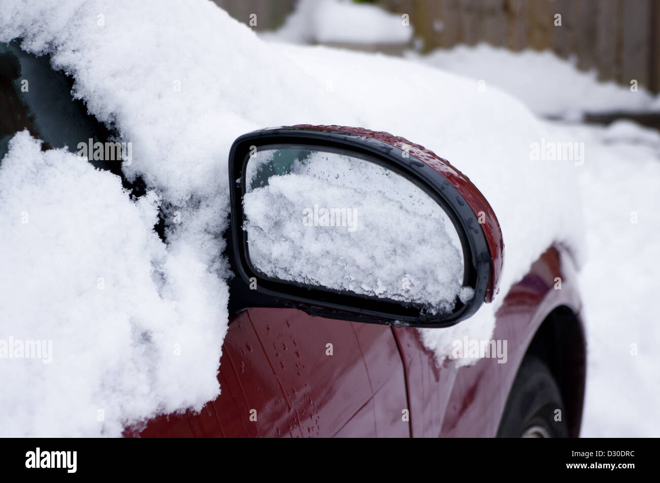 La fusione della neve da auto rossa specchietto laterale Foto Stock