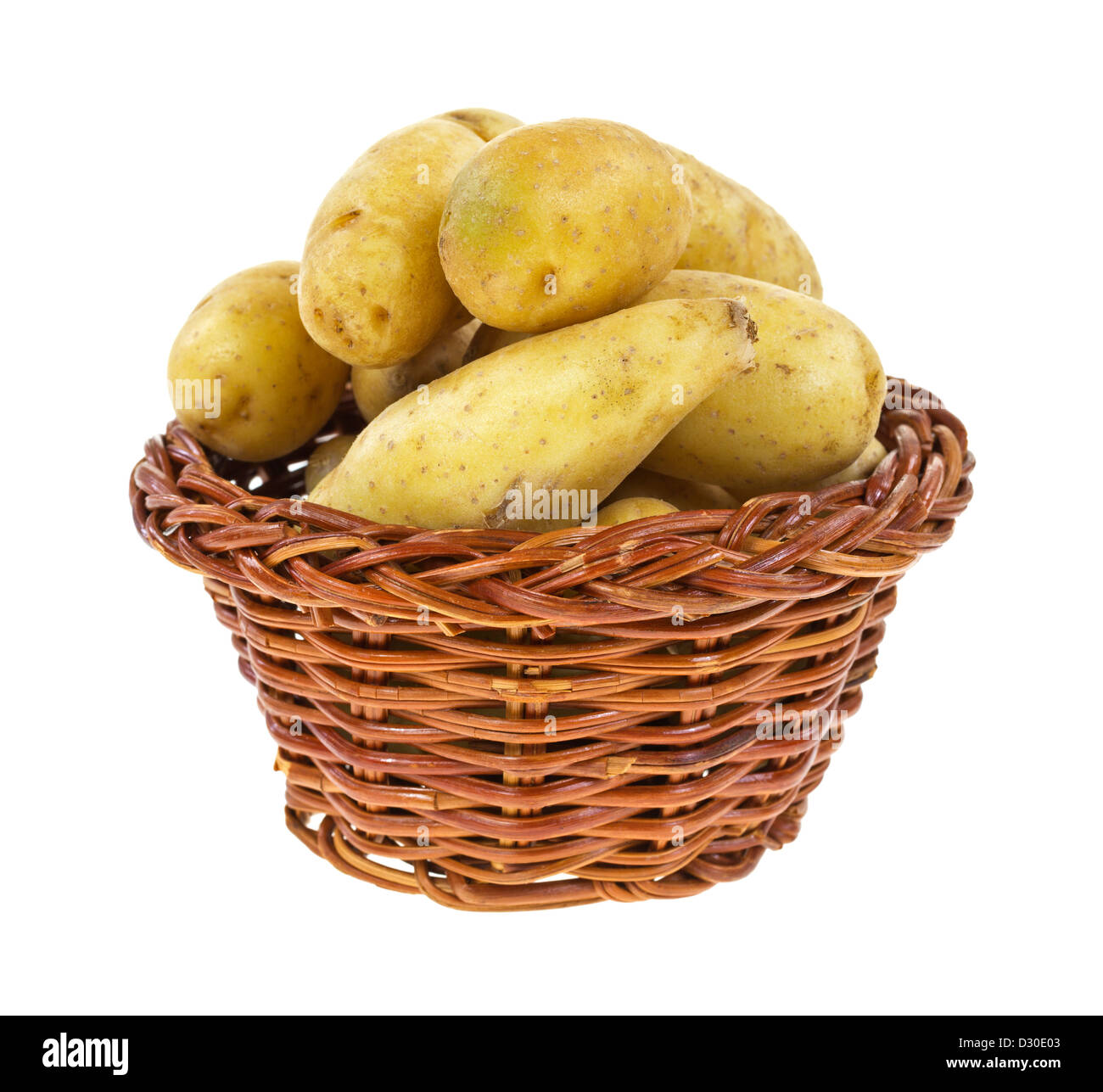 Un vecchio cesto di vimini riempito con giallo patate gourmet su uno sfondo bianco. Foto Stock
