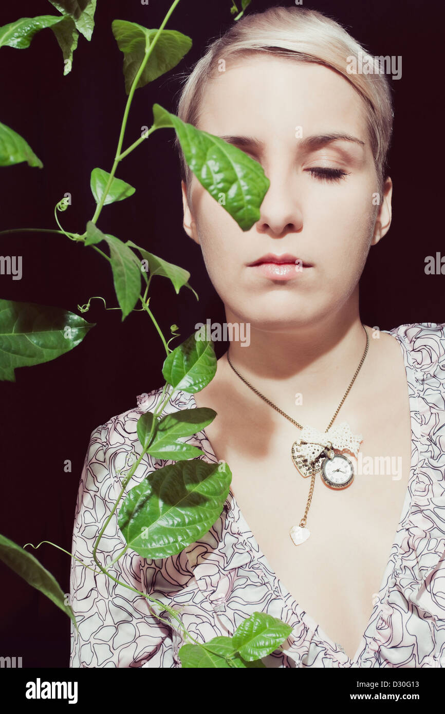 Ritratto di una giovane donna con una passione pianta da frutto su sfondo nero Foto Stock