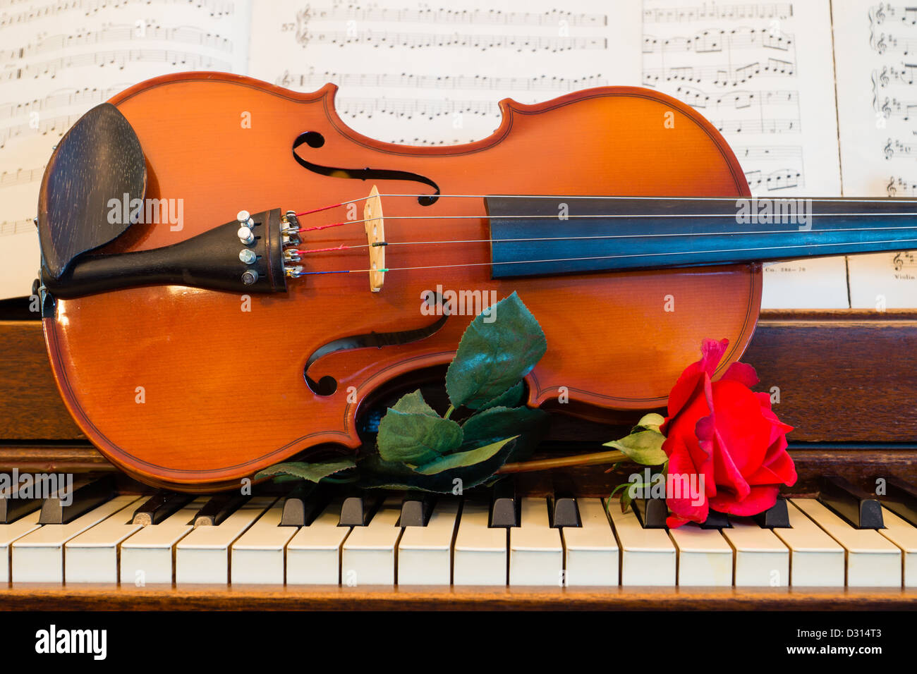 Una rosa, violino, e foglio di musica di sedersi su un pianoforte in  preparazione per una notte di musica Foto stock - Alamy