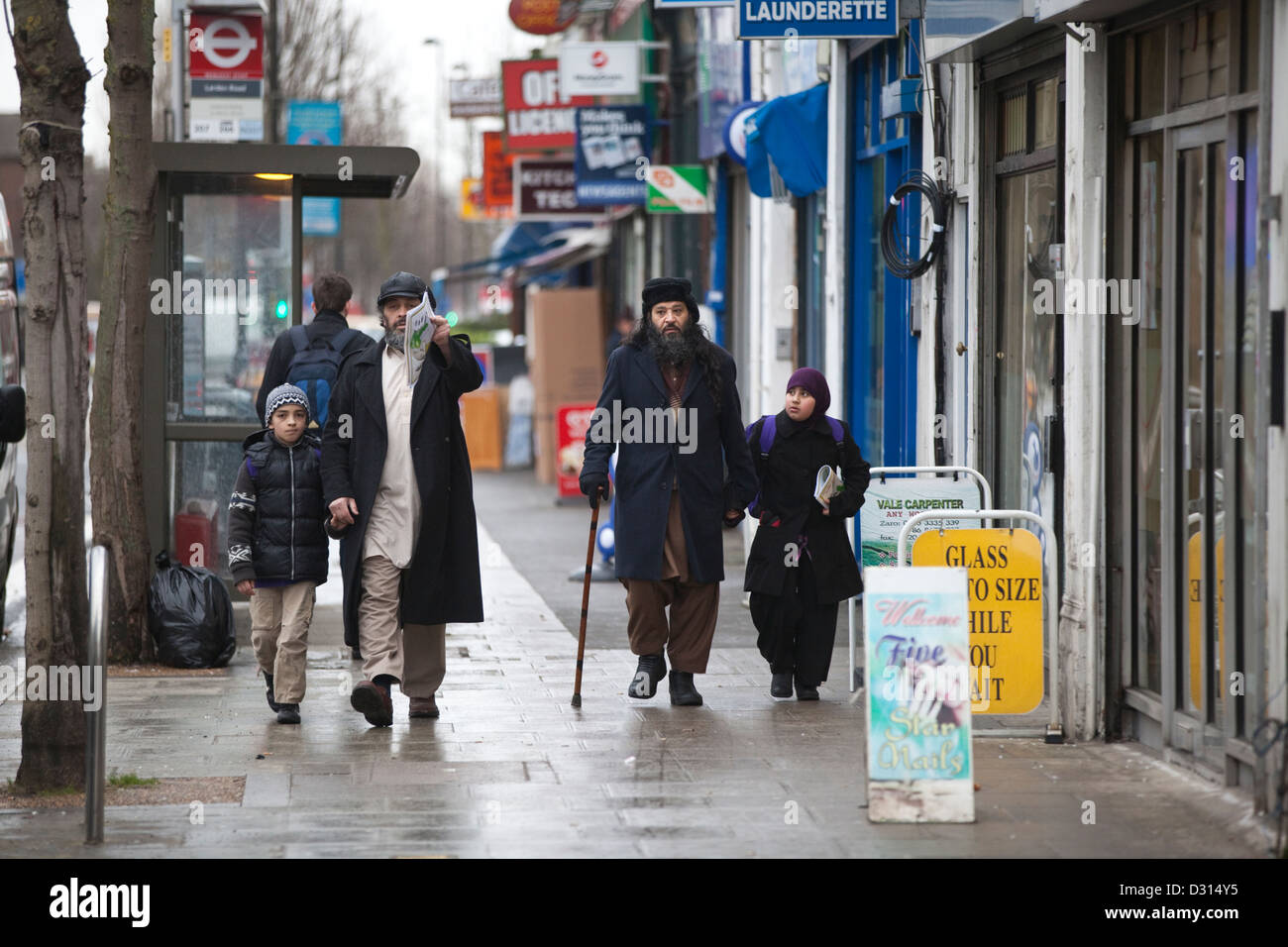 Uomini musulmani e i bambini a piedi lungo le strade di Acton Town, West London Foto Stock
