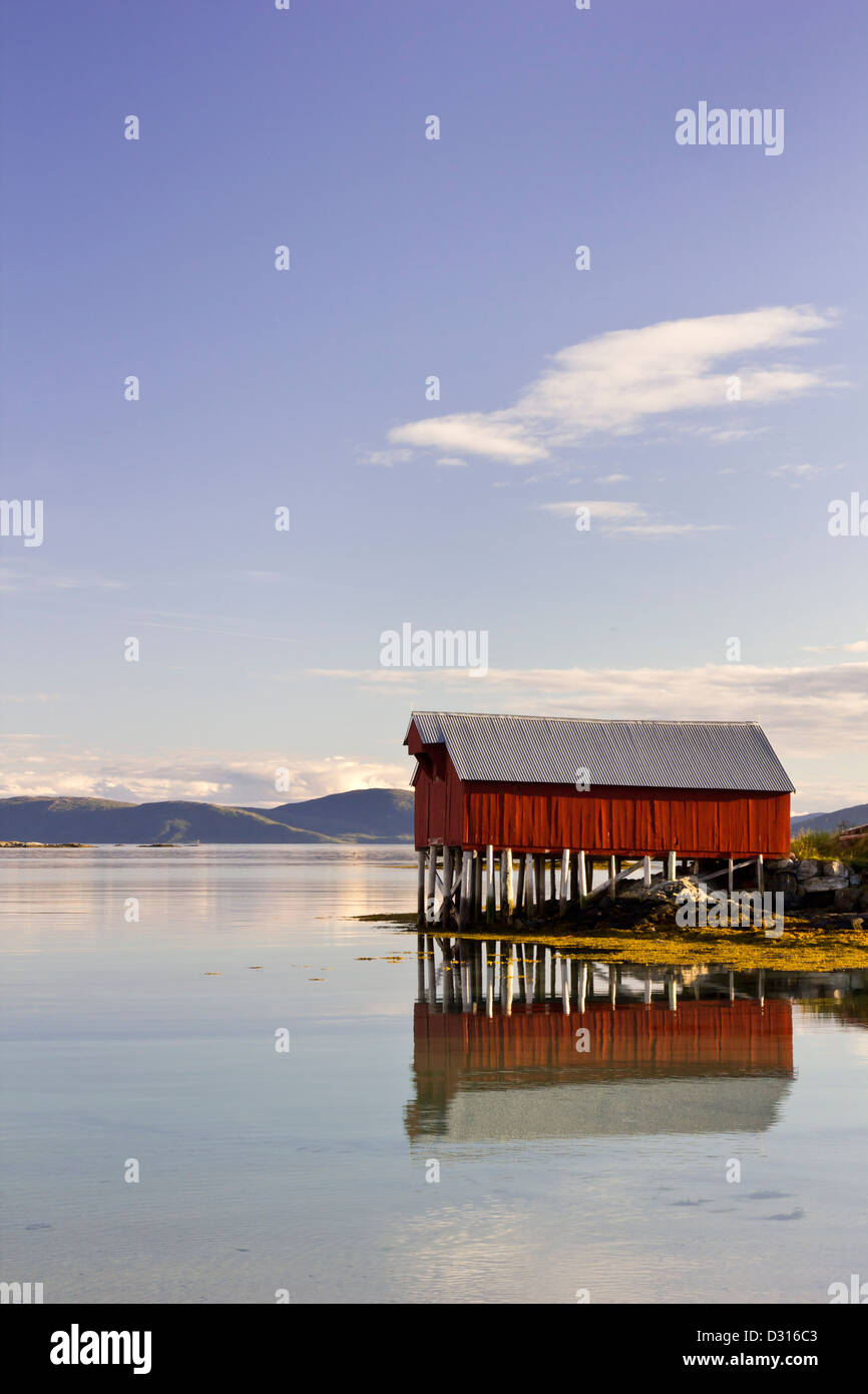 Bella tradizionali red boat house si riflette nelle calme acque del fiordo Foto Stock