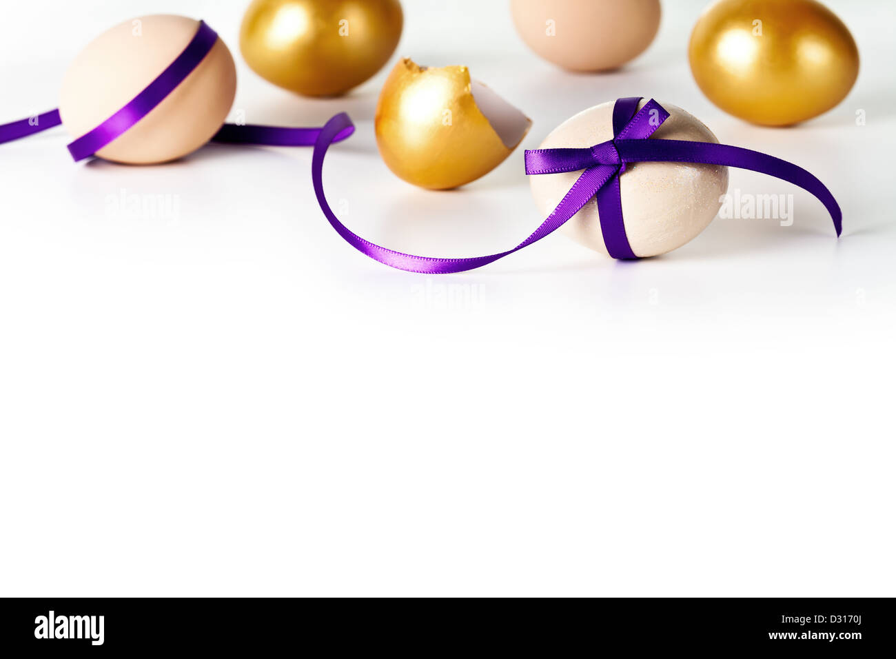 Uovo di Pasqua con prua violetto su sfondo bianco. Composizione con beige e oro uova Foto Stock