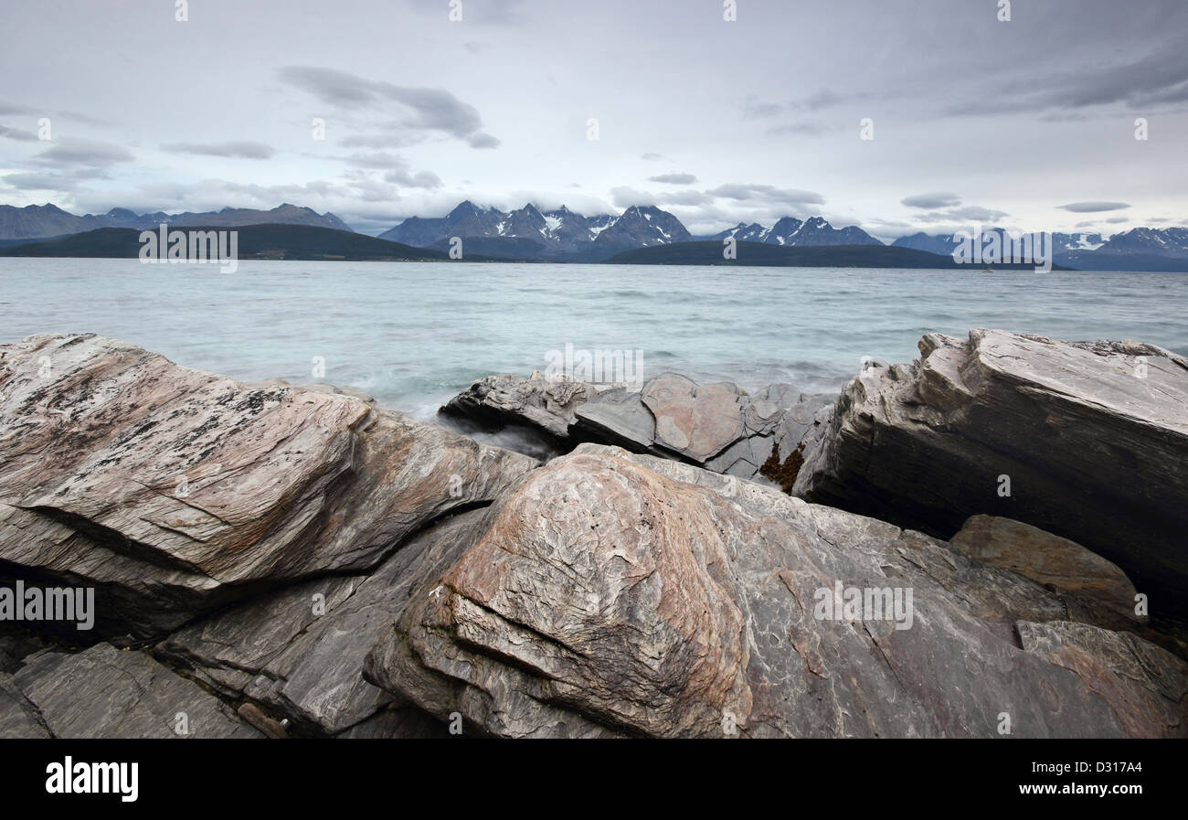 Grandi massi erosa sulle rive del Ullsfjord, attraverso l'acqua dalle possenti Alpi Lyngen - Norvegia settentrionale. Foto Stock