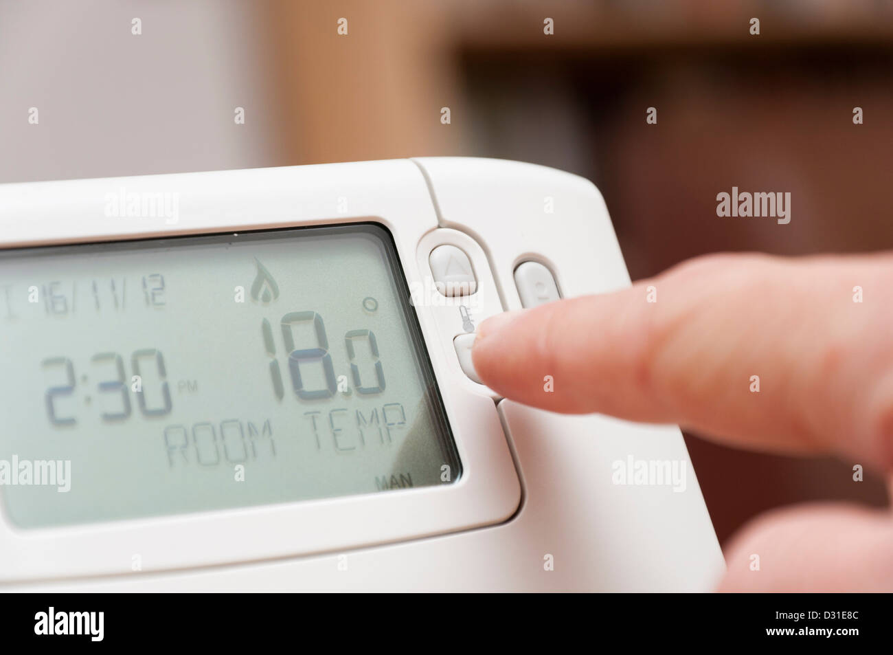 Regolazione della temperatura ambiente su un termostato di casa per risparmiare denaro sul riscaldamento bollette energetiche. Foto Stock