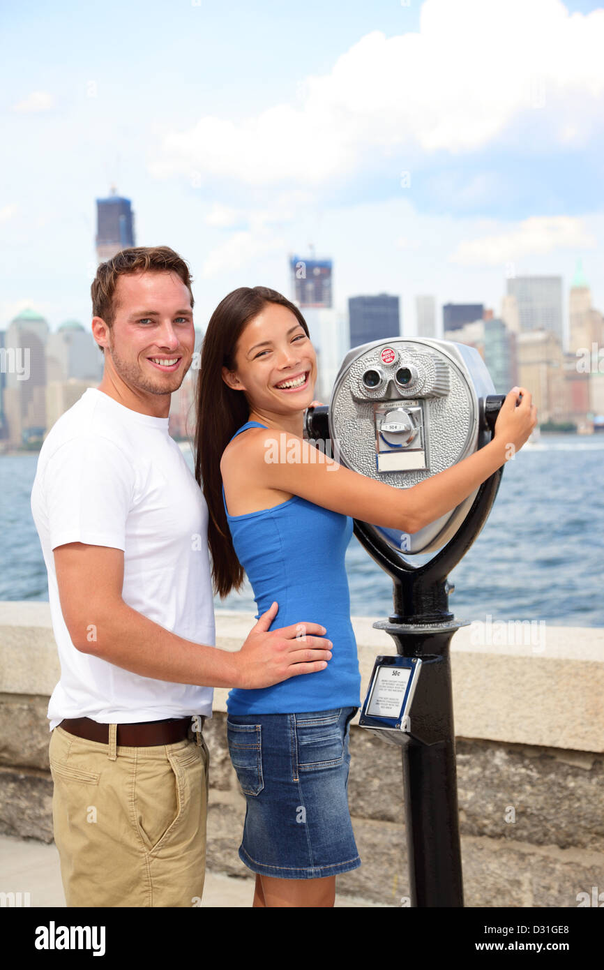 Giovane e bella interracial coppia giovane con un binocolo guardando a Manhattan e New York skyline della città da Ellis Island Foto Stock