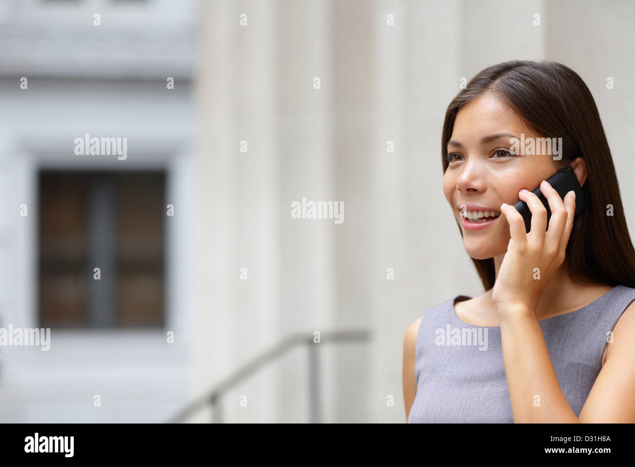 Giovane e bella gara di misto / caucasico asiatici professionali cinesi donna parlando su smart-phone all'aperto davanti al palazzo di giustizia Foto Stock