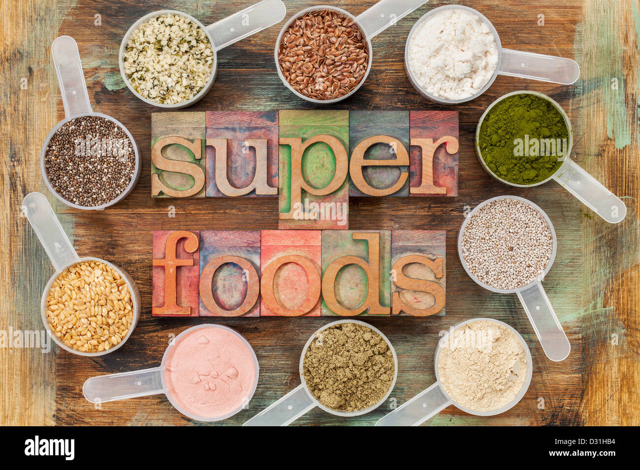 Superfoods word in rilievografia tipo legno circondato da palline di plastica di sementi sane e polveri Foto Stock