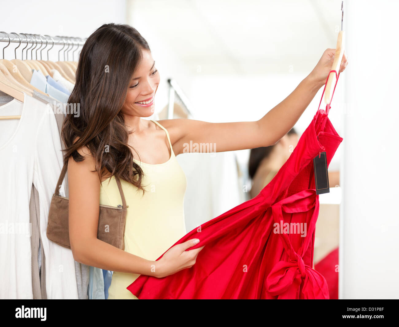 Bella multirazziale Asian / donna caucasica scegliendo abito rosso in negozio durante la vendita Foto Stock