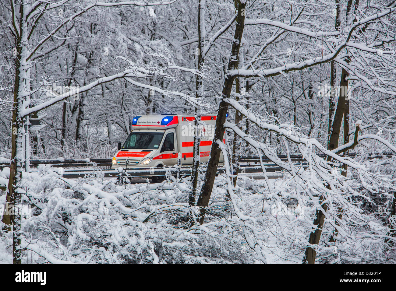 Ambulanza della Croce Rossa tedesca. In un funzionamento di emergenza, con luci lampeggianti, su una strada innevata in inverno Foto Stock