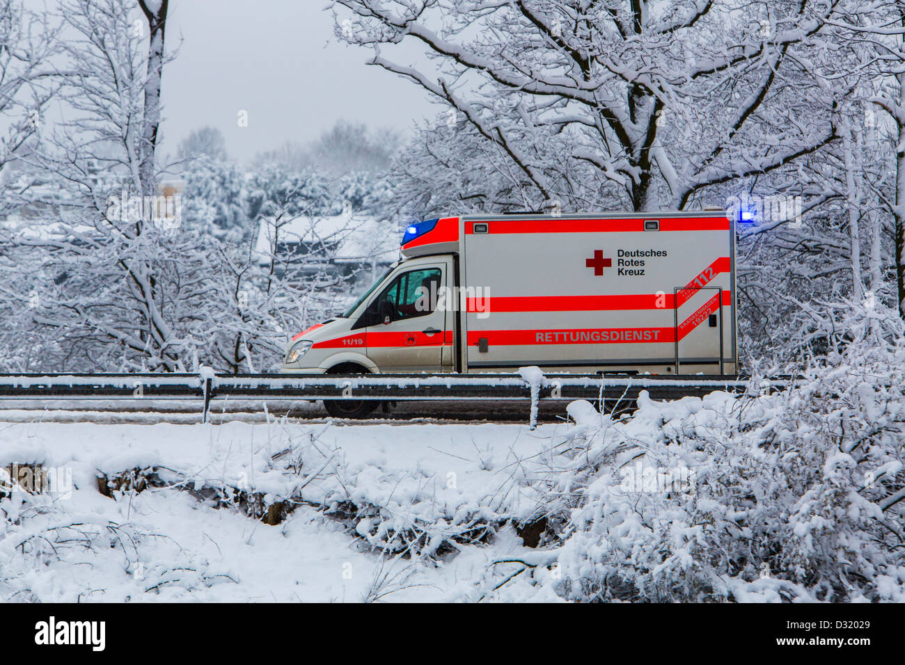Ambulanza della Croce Rossa tedesca. In un funzionamento di emergenza, con luci lampeggianti, su una strada innevata in inverno Foto Stock