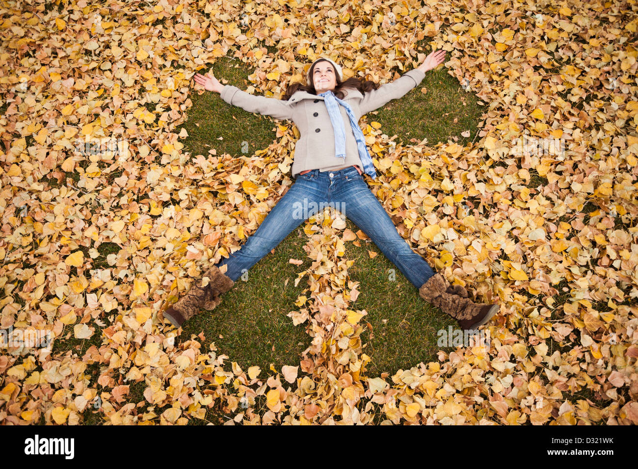 La donna caucasica rendendo angel in foglie di autunno Foto Stock