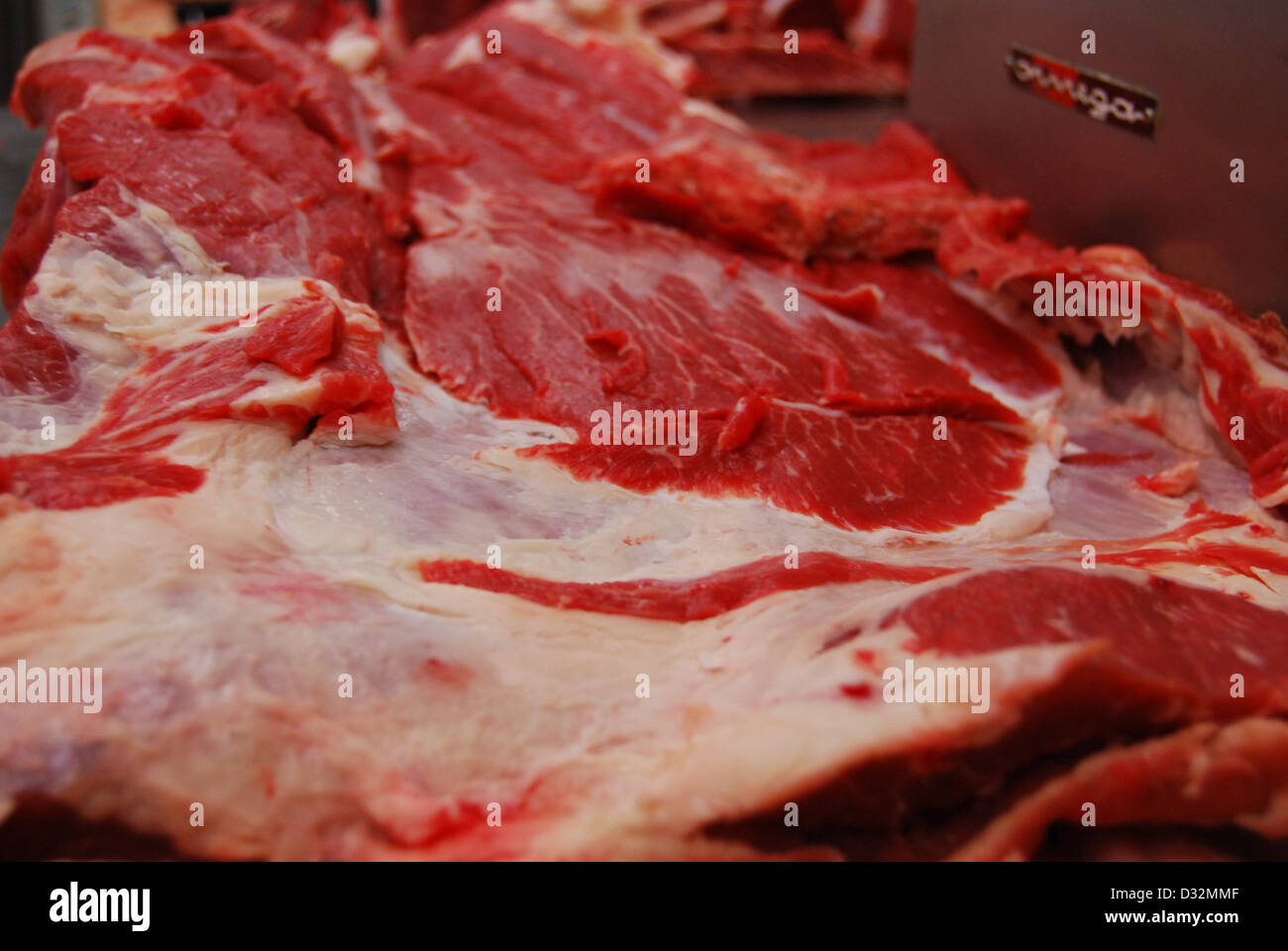 Rosso e bianco di lastre a base di carne e di ossa con grasso su una confusa macellai tabella pronto per essere tagliato e ordinati. Foto Stock