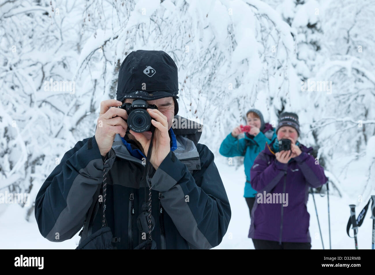 Tre persone scattano fotografie nella neve mentre è in vacanza Foto Stock