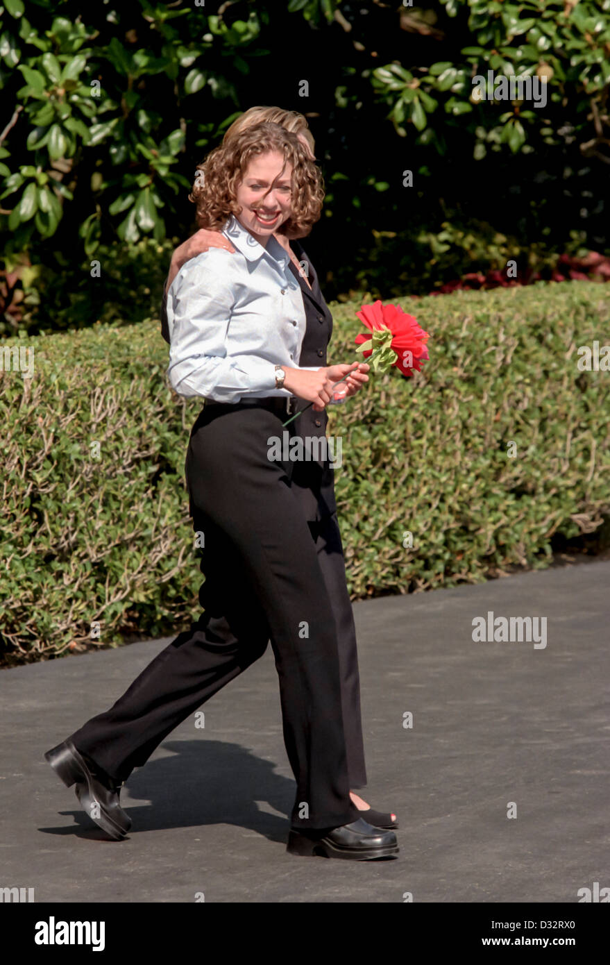 Chelsea Clinton tenendo un fiore di seta cammina con sua madre prima signora Hillary Rodham Clinton a bordo Marine un elicottero sul prato Sud della Casa Bianca Agosto 19, 1999 a Washington, DC. Il Clinton sono in viaggio per il Vigneto di Martha per una vacanza. Foto Stock