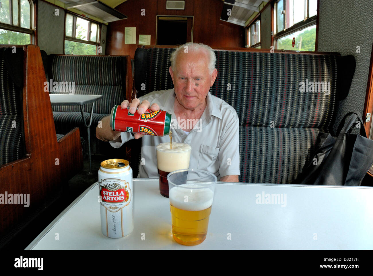 Titolare di pensione o di rendita versando un drink su un treno England Regno Unito Foto Stock