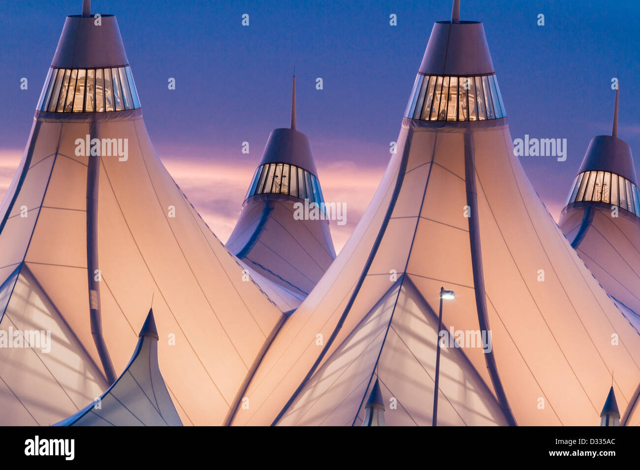 Incandescente tende di dia a sunrise. L'aeroporto internazionale di Denver ben noto per tetto a falde. design del tetto è riflettente montagne innevate. Foto Stock