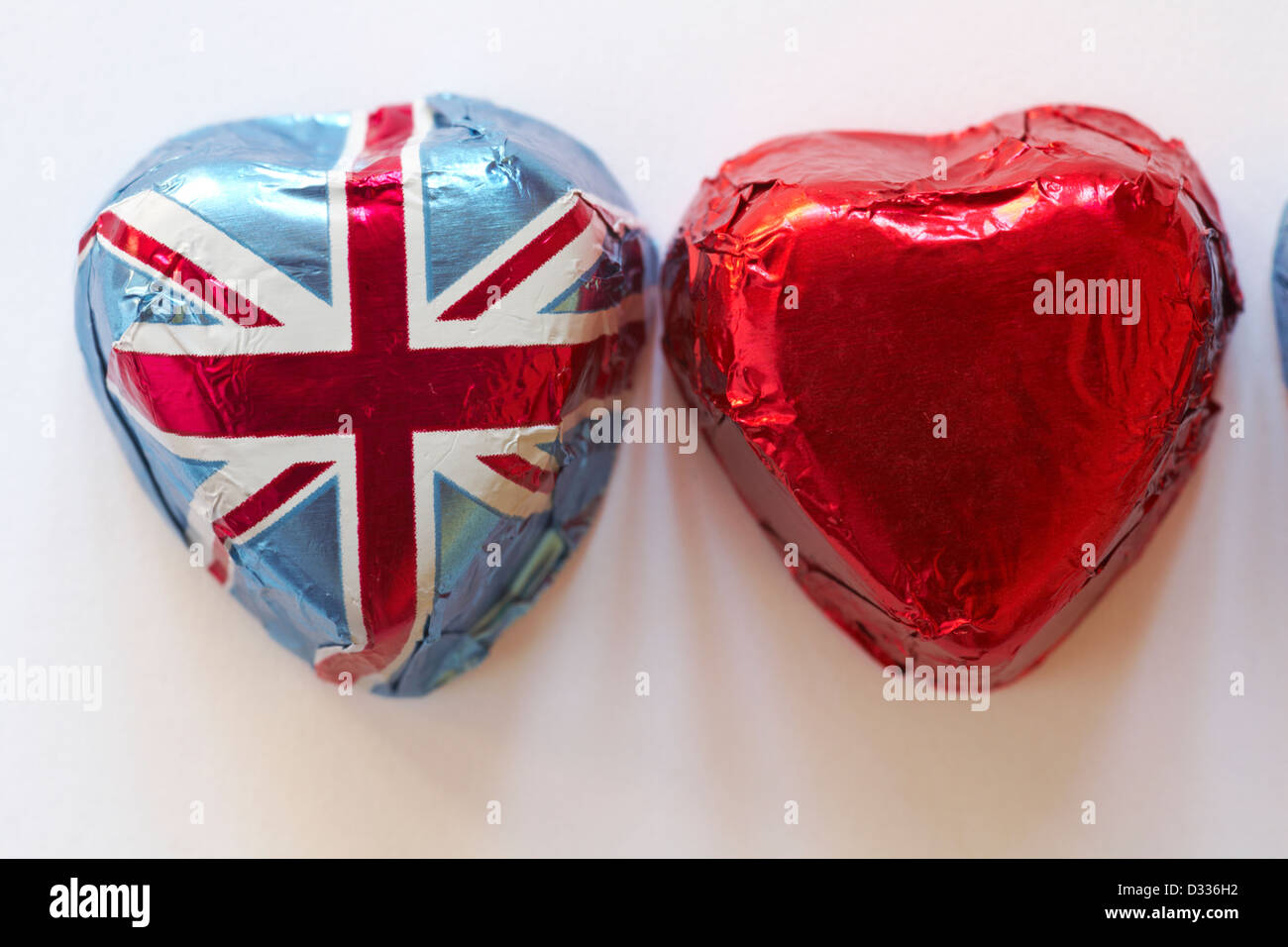 Due a forma di cuore ad cioccolatini, uno in Unione Jack involucro in foglio e uno in lamina di rosso isolato su sfondo bianco Foto Stock