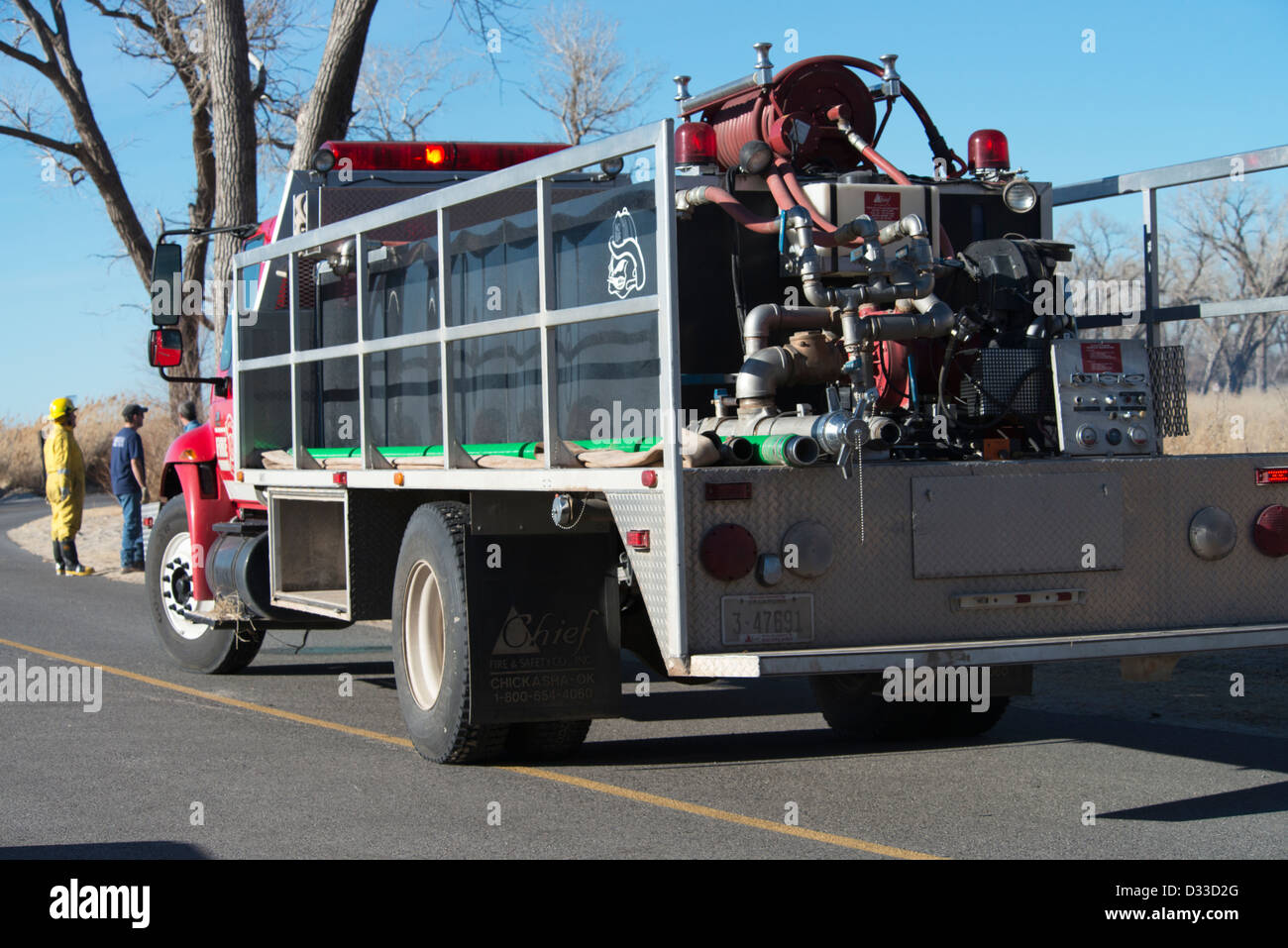 Un pumper firetruck è parcheggiato mentre un volontario unità antincendio mette fuori una spazzola fire in grande contea in Oklahoma, Stati Uniti d'America. Foto Stock