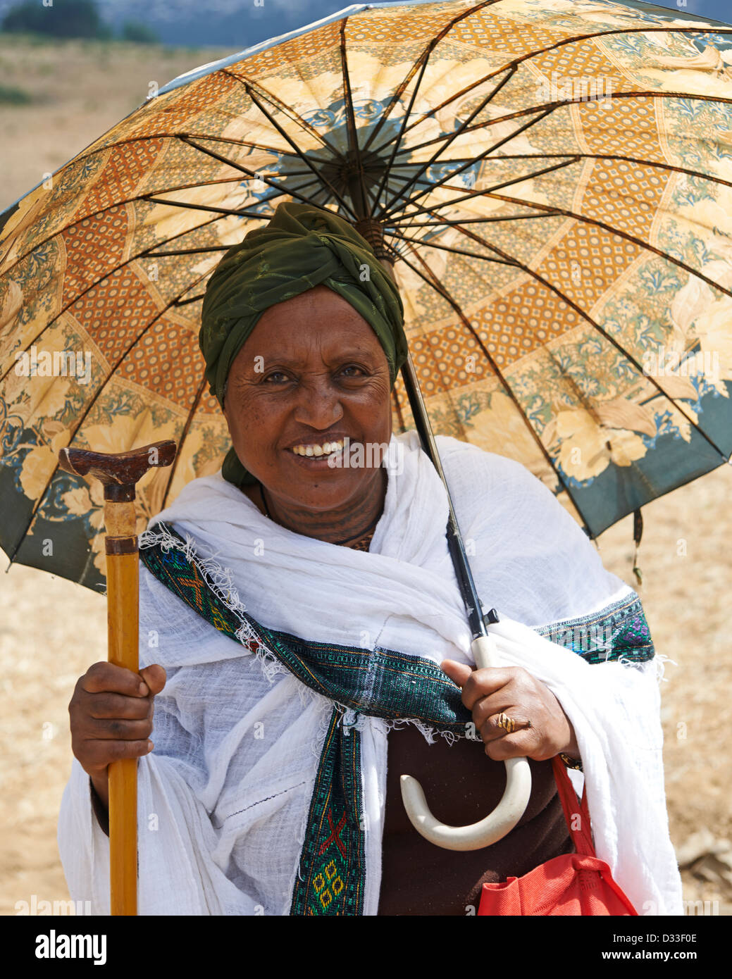 Un anziano donna con un ombrellone fa un pellegrinaggio al Badir Tar chiesa di montagna Foto Stock