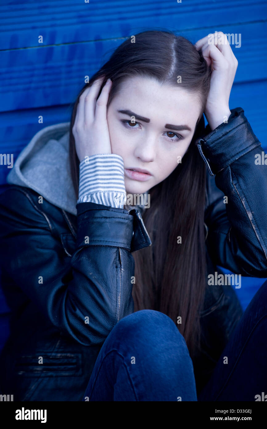 Un travagliato giovane ragazza adolescente seduto fuori. Foto Stock