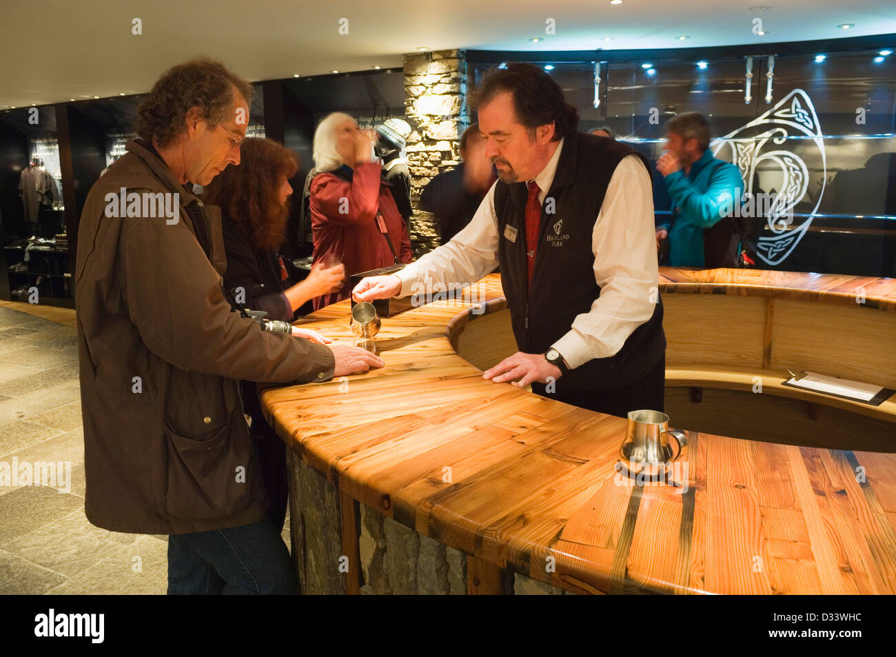 Una guida turistica versa una dram gratuito per un visitatore, nella sala di degustazione del whisky Highland Park distillery Visitor Centre. Foto Stock