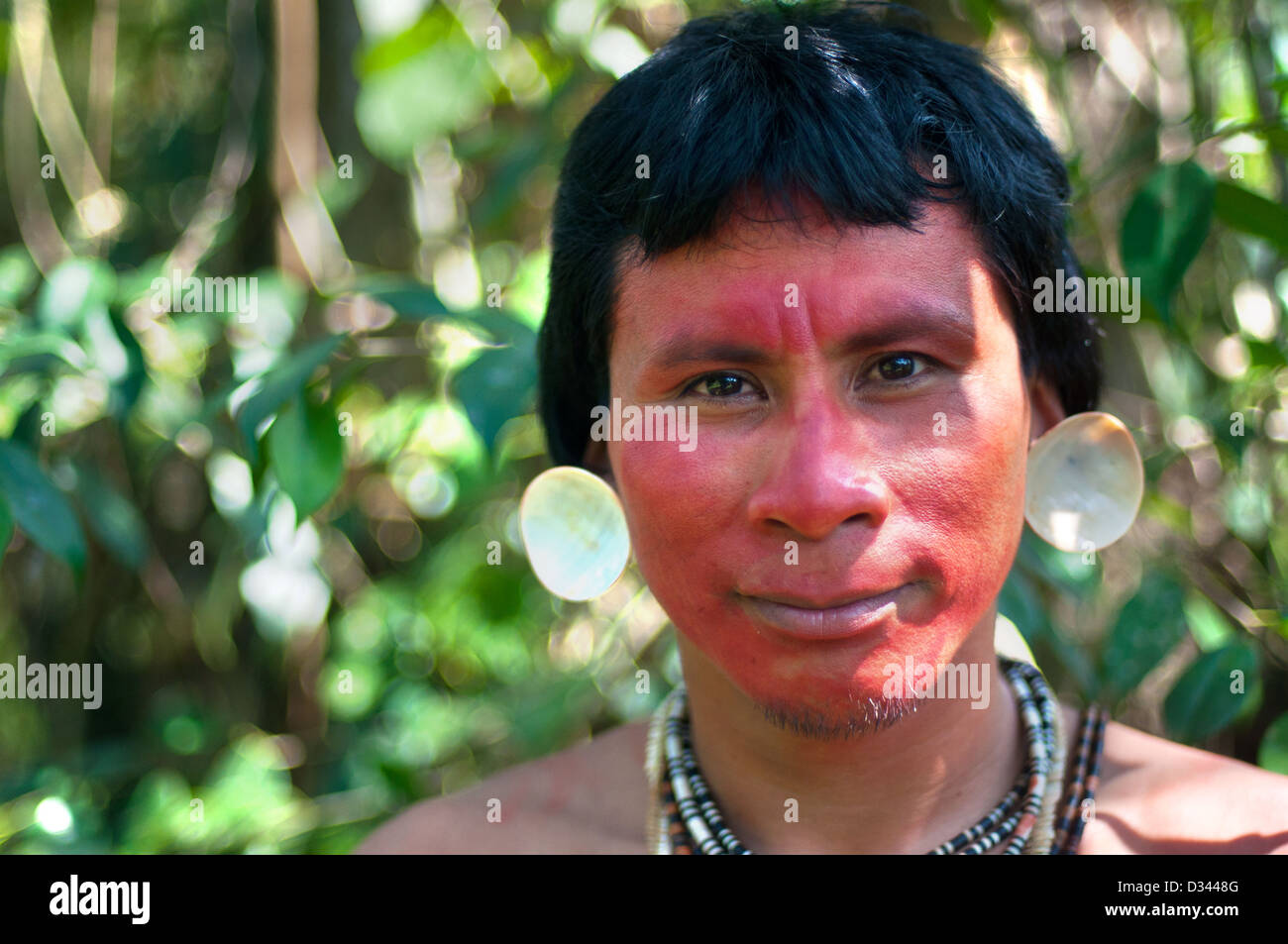 Un giovane uomo matis con tatuaggi facciali, gusci a suoi orecchi, vernice rossa (achiote) e le tradizionali collane, brasil Foto Stock