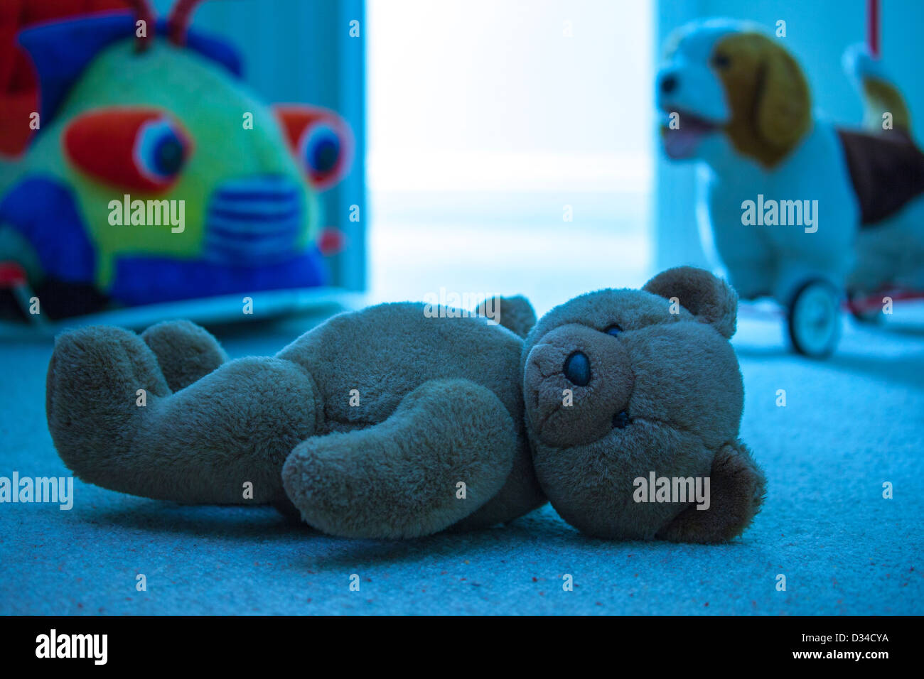 Brown orsacchiotto posa su un bambino il pavimento della camera. Le tonalità blu. Foto Stock