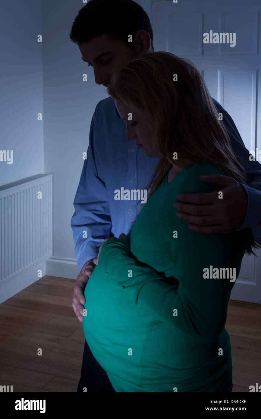 Giovane donna incinta e partner maschile profilarsi a casa. Foto Stock