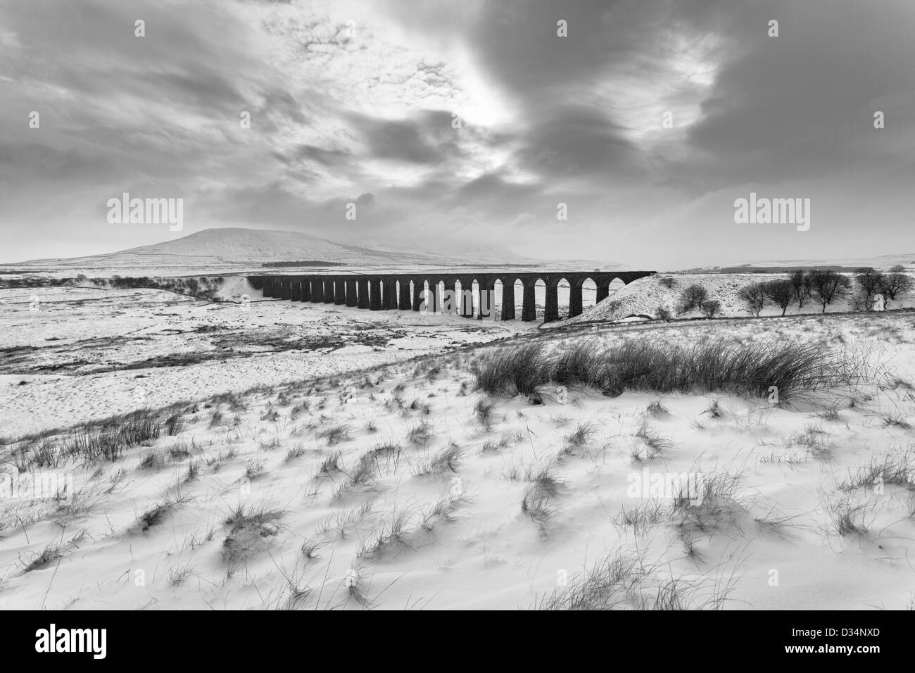 Immagine in bianco e nero del viadotto Ribblehead in inverno con neve sul terreno e Ingleborough avvolta nella nebbia e cloud. Foto Stock