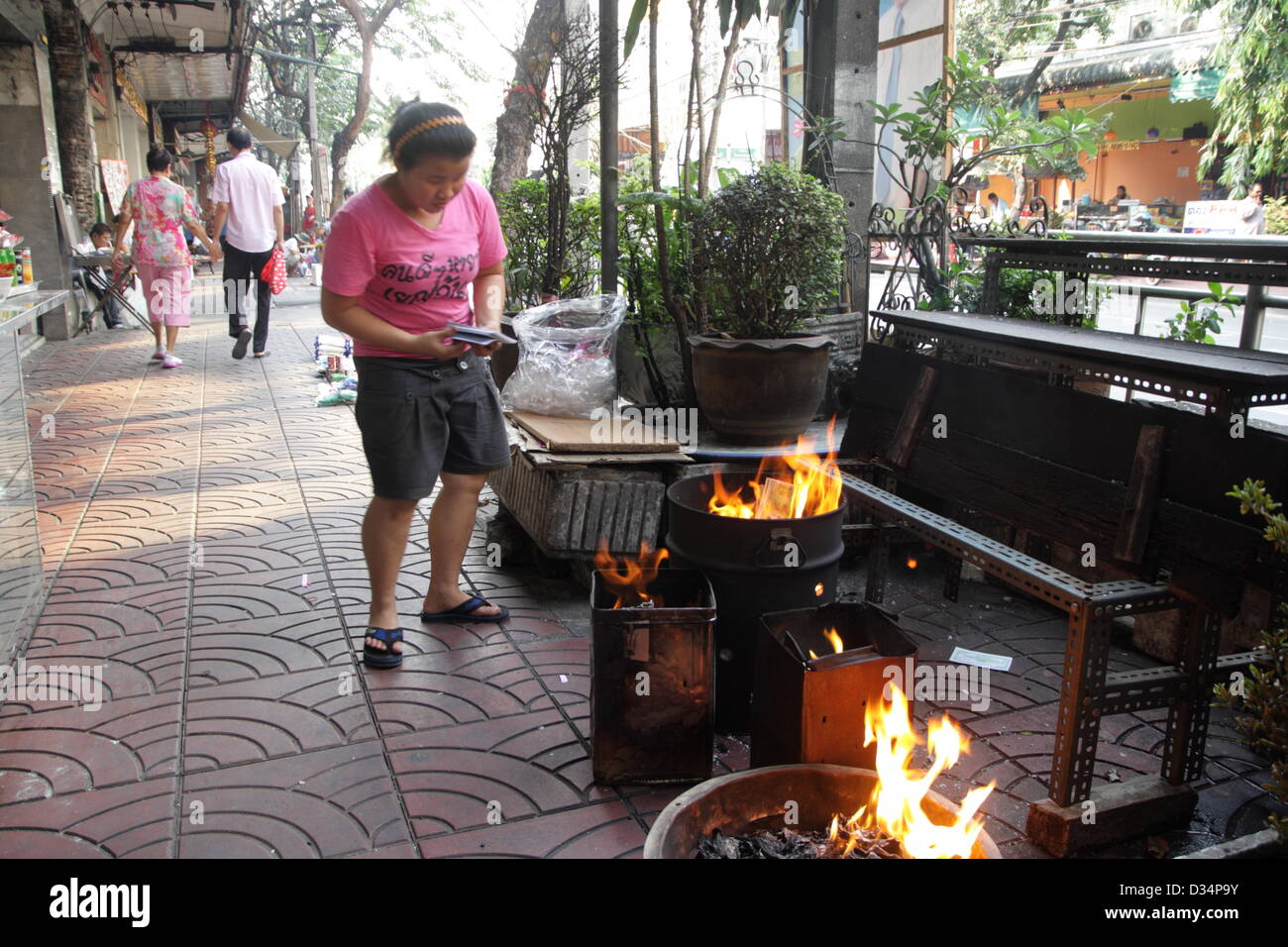 Bangkok , Thailandia .9 febbraio 2013. Una donna che brucia ''inferno soldi'' davanti a casa sua a Chinatown . Nuovo anno lunare cinese a Bangkok Chinatown il 9 febbraio 2013. Il nuovo anno cinese del serpente cade il 10 febbraio. Il prossimo anno sarà l'"Anno del serpente'' in zodiaco cinese. Credito: John Vincent / Alamy Live News Foto Stock