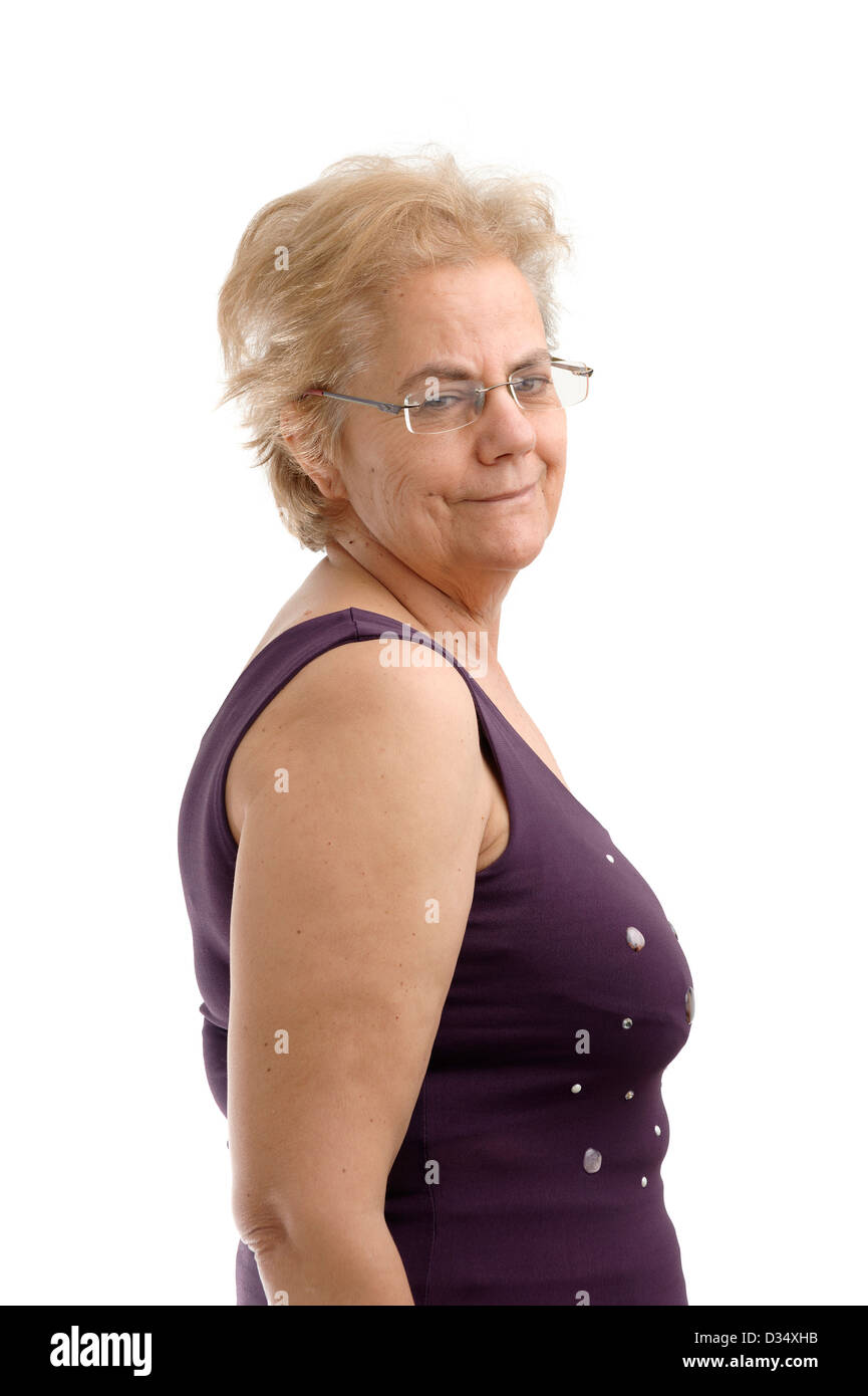 Fiducioso donna di mezza età che indossa un viola camicia senza maniche e guardando sopra la sua spalla destra isolati su sfondo bianco Foto Stock