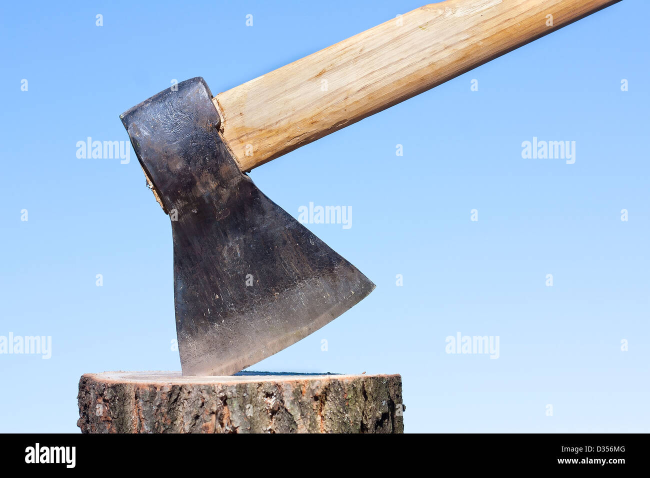 Ax o legno trinciatore nel log contro un cielo blu Foto Stock