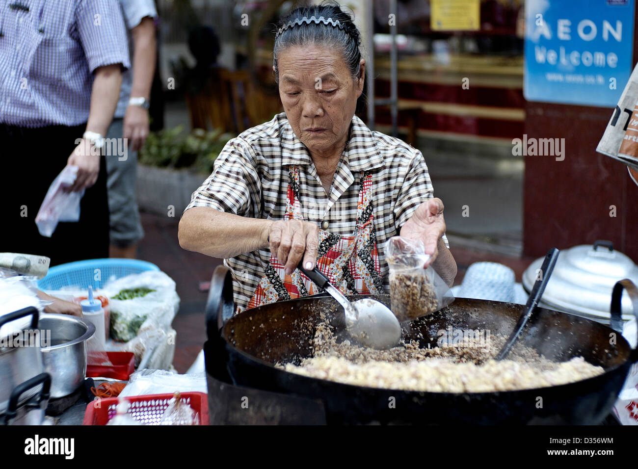Anziani Thai femmina fornitore di cibo che serve su una strada di Bangkok. Thailandia street food. S. E. Asia Foto Stock