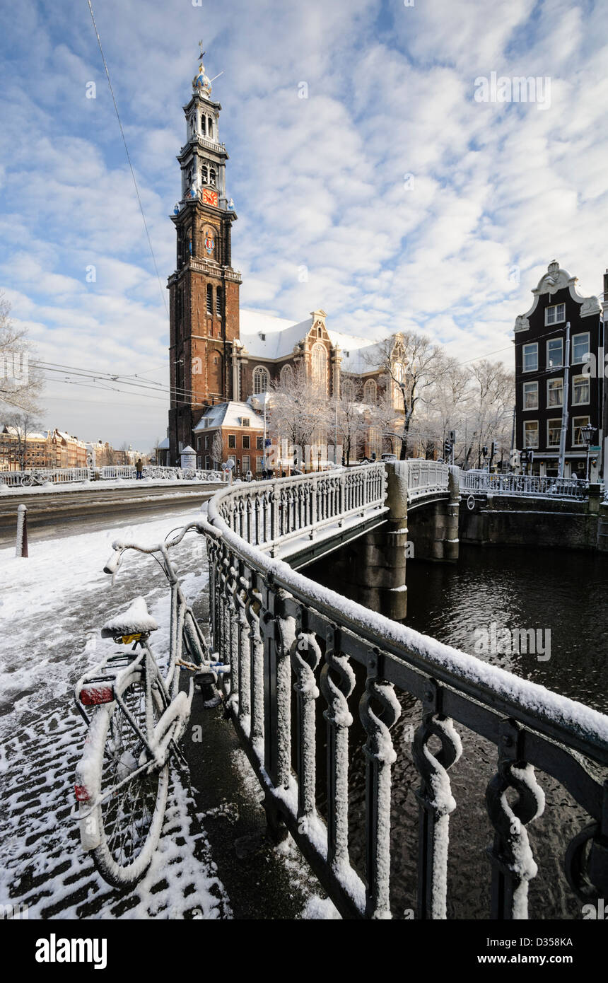 Coperta di neve ponte sul canale Prinsengracht, con Westerkerk in background, Amsterdam, Paesi Bassi Foto Stock